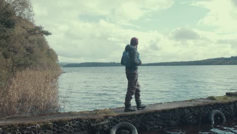 Kayaker-wearing-life-jacket-walks-down-pier-at-lake