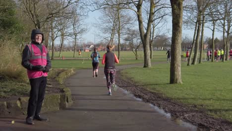 Active-fitness-group-jogging---walking-in-wet-rainy-park-in-slow-motion-Marshall-watching-runners