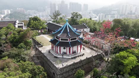 Vista-Aérea-De-La-Capilla-Del-Centro-Cristiano-Tao-Fong-Shan,-Sha-Tin,-Hong-Kong-Con-El-Horizonte-De-La-Ciudad-Al-Fondo