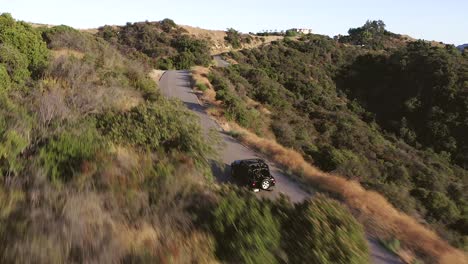 Toma-Aérea-Cinematográfica-De-Un-Jeep-Negro-Conduciendo-Por-Una-Carretera-Asfaltada-En-Las-Colinas-De-Los-ángeles