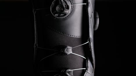 A-close-up-shot-of-snowboard-boots-against-black-background,-abstract-pattern,-black---white-design,-with-black-empty-negative-space,-room-for-text-and-title,-vivid-light-fall-off-and-highly-detailed