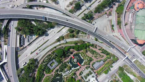 Tráfico-De-Vista-Aérea-De-Arriba-Hacia-Abajo-En-Múltiples-Carreteras-Con-El-Pabellón-De-La-Perfección-Absoluta-Y-El-Jardín-De-Nan-Liana-En-El-Corazón-De-Hong-Kong