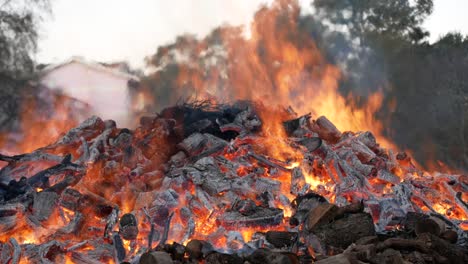 People-passing-by-festive-giant-wood-bonfire,-celebrate-traditional-holiday-in-Portugal