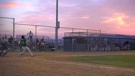 Clip-En-Cámara-Lenta-De-Un-Bateador-Golpeando-Un-Jonrón-Y-Corriendo-A-Primera-Base-En-Un-Juego-De-Béisbol-De-Ligas-Menores-Durante-La-Puesta-De-Sol