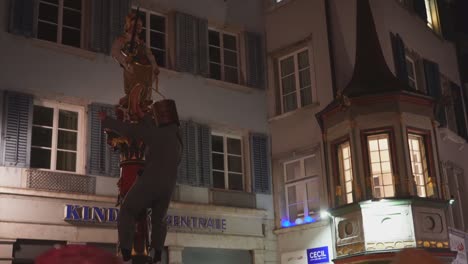 Betrunkene-Person-In-Kostüm-Und-Eimer-Auf-Dem-Kopf-Tanzt-Im-Freien-In-Der-Stadt-Und-Hält-Sich-An-Der-Statue-Fest