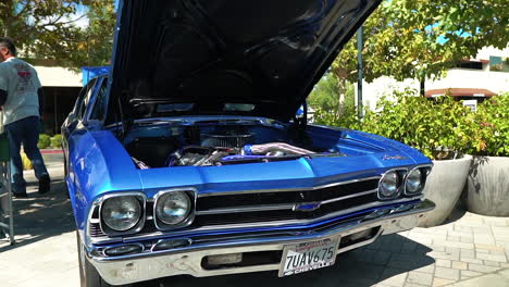 Blue-late-1960s-Chevelle-on-display-at-car-show-with-hood-open,-tracking