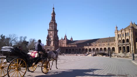 Los-Turistas-Viajan-En-Carruaje-Tirado-Por-Caballos-En-La-Plaza-De-España,-Sevilla,-España,-Cámara-Lenta