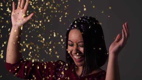 Young-woman-dancing-with-joy-in-a-golden-rain-of-confetti---Slow-motion