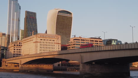 Autobús-Británico-Rojo-Conduciendo-Por-El-Puente-Hacia-Los-Edificios-De-La-Torre-De-Oficinas-Corporativas