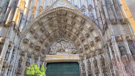 The-Cathedral-of-Saint-Mary-of-the-See,-Seville-Cathedral-on-a-sunny-day-with-blue-sky-in-Andalusia-Spain,-tilting-up