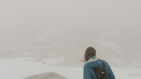 Una-Mujer-Contempla-Una-Vista-De-Un-Entorno-Nevado,-Desolado-Y-De-Gran-Altitud-A-Través-De-Una-Espesa-Niebla,-Cámara-Lenta-Estática