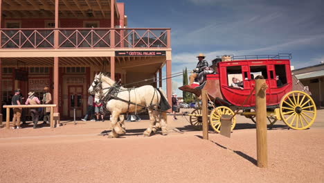 Touristen,-Die-In-Der-Traditionellen,-Von-Pferden-Gezogenen-Postkutsche-In-Der-Allen-Street-Tombstone,-Arizona,-Unter-Dem-Sonnigen-Tag-Herumgefahren-Werden