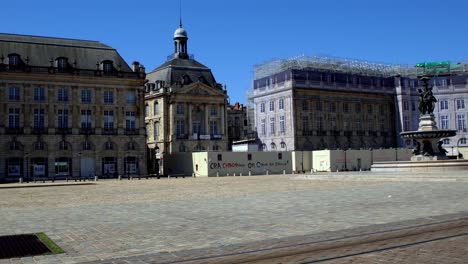 Place-de-la-Bourse-empty-square-due-to-the-COVID-19-pandemic-and-with-graffiti-on-construction-walls,-Dolly-right-shot