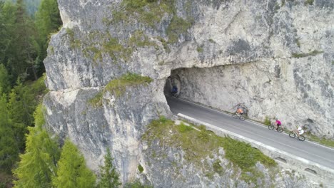 Antena-De-Un-Ciclista-Masculino-Entrando-En-Un-Túnel-En-Los-Dolomitas-Italianos-Mientras-Otros-Ciclistas-Se-Están-Poniendo-Al-Día