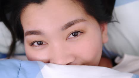 Closeup-of-Female-Smiling-and-Looking-at-Camera-and-lovely-Lies-in-Bed-Covered-with-Blanket