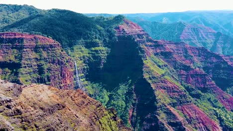 HD-Hawaii-Kauai-slow-motion-boom-up-and-slight-pan-left-to-right-from-a-few-pieces-of-long-grass-in-lower-left-to-Waimea-Canyon-with-a-waterfall-in-distance