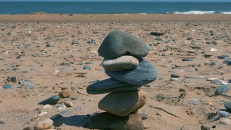 Equilibrio-De-Piedra-En-La-Playa-De-La-Bahía-De-Brittas,-Con-Un-Niño-Pequeño-Corriendo-Hacia-El-Agua-En-El-Fondo-En-El-Condado-De-Wicklow,-Irlanda-En-Verano