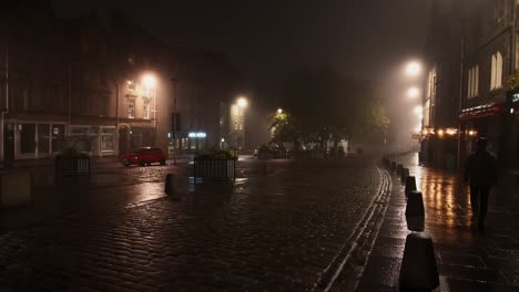 Person-walking-at-empty-Grassmarket-in-Edinburgh-on-a-foggy-quiet-night
