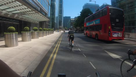 POV-Of-Cyclisst-Riding-Down-North-Colonnade-In-Canary-Wharf-With-Bus-Going-Past