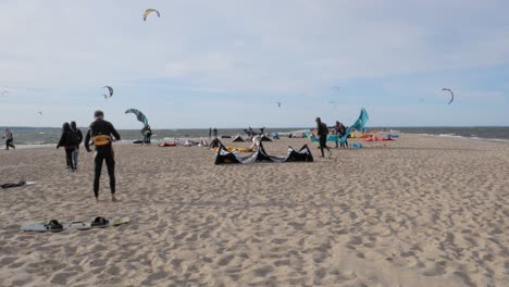 Gente-En-La-Orilla-Preparando-Sus-Cometas-Eléctricas-Para-Hacer-Kiteboarding-En-Rewa,-Polonia---Plano-General