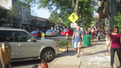 Artist-on-sidewalk-among-crowds-during-community-art-festival,-Slow-Motion