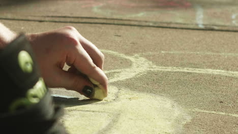 Youthful-hand-grinding-chalk-onto-city-sidewalk,-Close-Up,-Slow-Motion