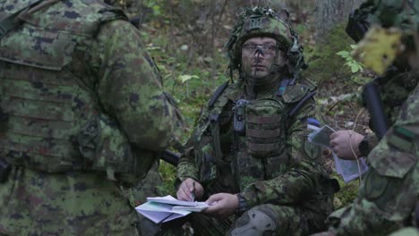 Soldiers-in-camouflage-planning-strategy-in-the-forest,-wide-shot,-handheld,-slow-motion