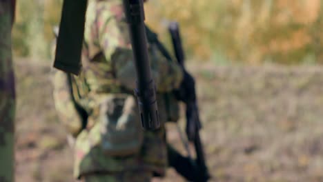 Rifle-barrel-foreground-soldier-holding-a-rifle-in-the-background,-slow-motion