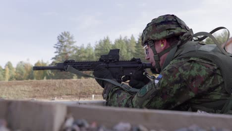 Soldier-laying-down,-aiming-and-firing-assault-rifle-in-military-exercise,-midshot,-handheld