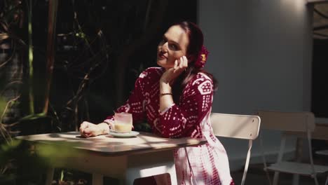 woman-sitting-alone-at-an-outdoor-dinning-table-at-a-restaurant-taking-a-beverage