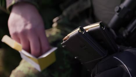 Hands-load-rifle-magazine-with-bullets,-closeup,-handheld