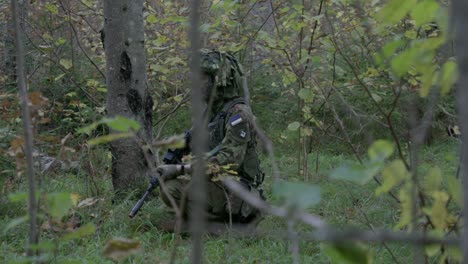 Soldado-En-Camuflaje-Arrodillado,-Acechando-En-El-Bosque,-Cámara-Lenta,-Portátil