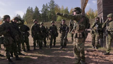 Group-of-soldiers-trained-by-instructor-about-aiming-firearm,-handheld,-wide-shot