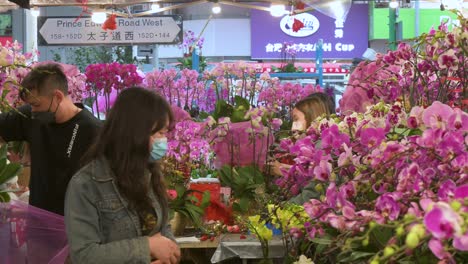 Los-Compradores-Chinos-Compran-Flores-Y-Plantas-Decorativas-Del-Tema-Del-Año-Nuevo-Chino,-Como-Orquídeas,-En-Un-Puesto-Callejero-Del-Mercado-De-Flores-Antes-De-Las-Festividades-Del-Año-Nuevo-Chino-Lunar