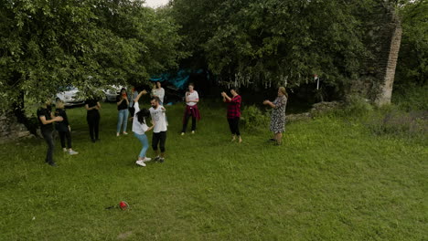 Georgian-family-dancing-and-celebrating-in-grassy-meadow-under-trees