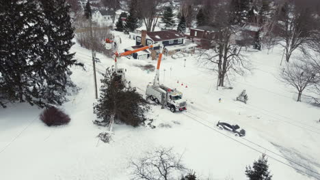 Workers-fix-powerlines-by-fallen-tree-after-blizzard-in-Canada,-aerial