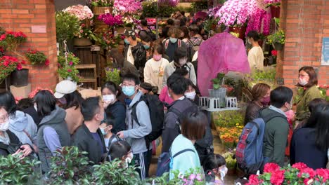 Shoppers-buy-decorative-Chinese-New-Year-theme-flowers-and-plants,-such-as-orchids,-at-a-flower-market-street-stall-ahead-of-the-Lunar-Chinese-New-Year-festivities