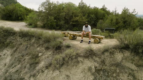 Bearded-traveler-sitting-on-cliff-bench-in-Vashlovani,-taking-a-break