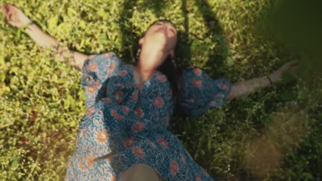 Cheerful-young-woman-laying-down-on-flowers-in-a-field-with-legs-lifted-in-the-air