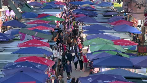 Bird's-eye-view-of-an-overcrowded-Fa-Yuen-street-stall-market-during-nighttime-as-people-look-for-bargain-priced-vegetables,-fruits,-gifts,-and-fashion-goods-in-Hong-Kong