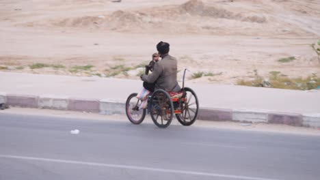 A-disabled-man-drives-his-hand-pedals-wheelchair-along-an-african-avenue