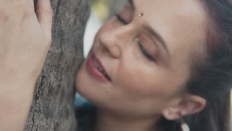 Up-close-of-a-beautiful-young-woman-looking-and-posing-against-tree