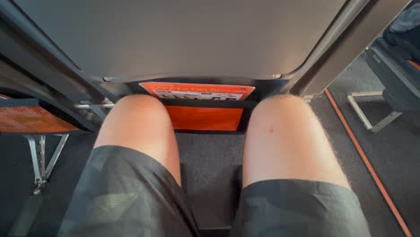 Viajar-En-Un-Asiento-De-Avión-Apretado-Con-Muy-Poco-Espacio-Para-Las-Piernas-En-Las-Aerolíneas-Easyjet,-Piernas-Y-Rodillas-Masculinas-Apretadas-En-Un-Avión-Easyjet,-Asiento-Incómodo,-Toma-De-4k