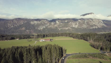 Aerial-drone-of-beautiful-alpine-mountain-range-in-the-distance-with-grassy-fields-and-trees
