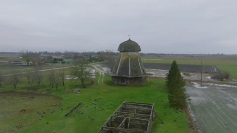 Beautiful-aerial-establishing-view-of-old-wooden-windmill-in-the-middle-of-the-field,-Prenclavu-windmill-,-overcast-winter-day,-wide-drone-point-of-shot