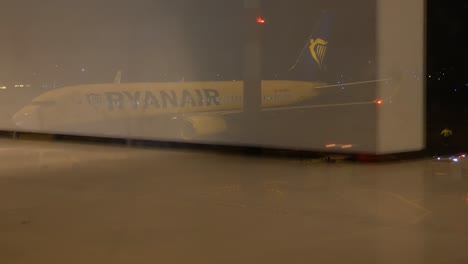 People-reflection-walk-inside-airport-while-Ryanair-jet-liner-is-being-prepared,-time-lapse