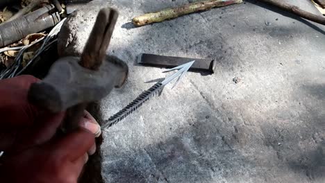 Datoga-tribe-man-hammering-a-handmade-arrow-on-a-rock-outside
