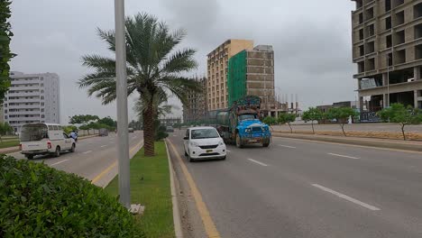 Dolly-Right-Reveal-Of-Traffic-Passing-Along-Highway-Road-Beside-Developments-At-Bahria-Housing-Development-In-Karachi