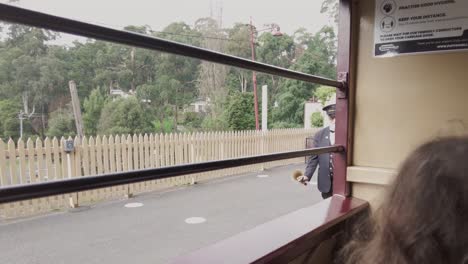 The-conductor-of-the-Puffing-Billy-steam-train-in-Melbourne,-Australia-ensuring-that-passengers-are-ready-to-go-and-ringing-the-bell