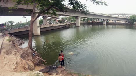 Young-people-swimming-in-a-pond-in-the-busy-city-of-Bangladesh,-Dhaka